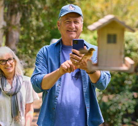 man taking a photo of a birdhouse with his partner